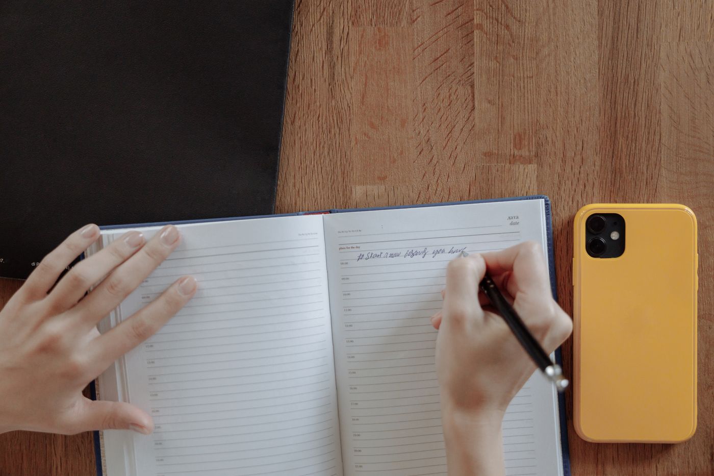 A person writing in a notebook at their desk
